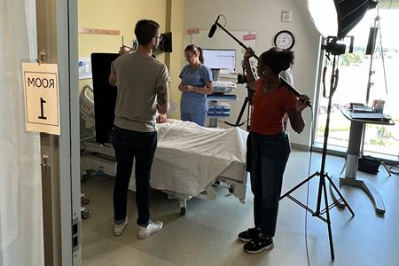 Image of Ashley Perry next to hospital bed and film equipment